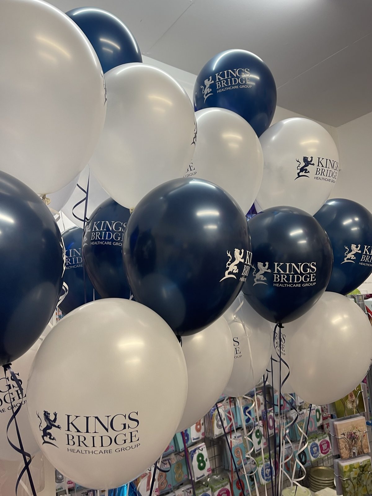 White and midnight blue pearl balloons printed with the Kings Bridge logo in contrasting ink colours