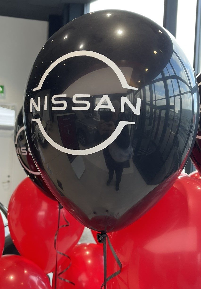 Nissan logo printed in white on shiny black latex balloons, arranged in floor-height sets of three